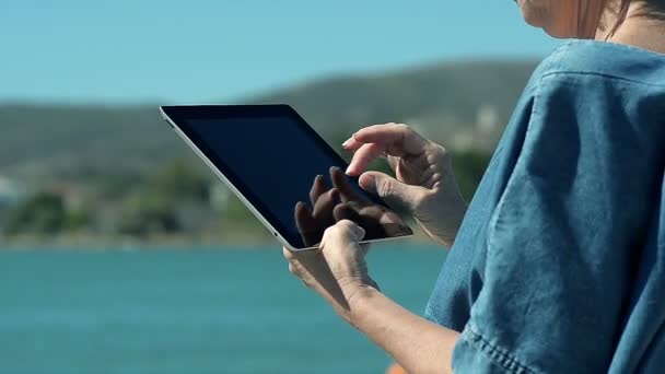 Крупним планом жінці за допомогою планшетного ПК на березі моря — стокове відео