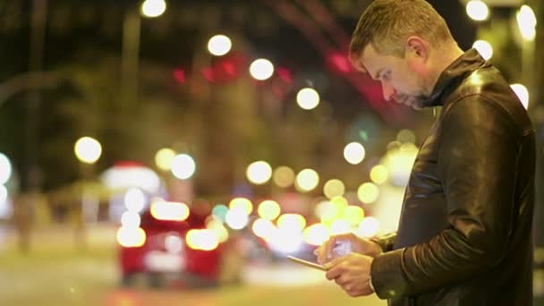 Jovem usando IPad na cidade da noite — Vídeo de Stock