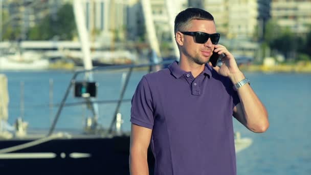 Мужчина разговаривает по телефону на пристани — стоковое видео