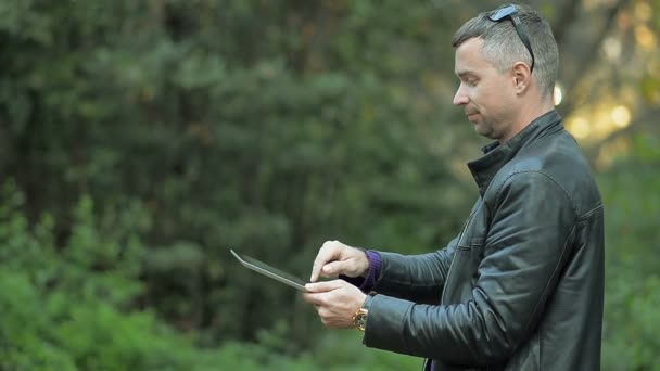 Jeune homme avec une tablette dans le parc — Video