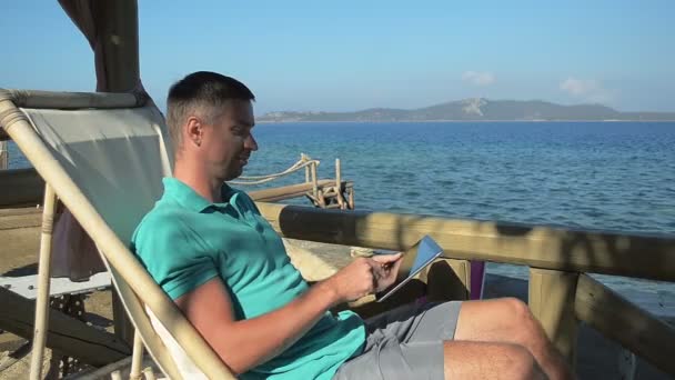 Joven usando IPad en la costa — Vídeos de Stock