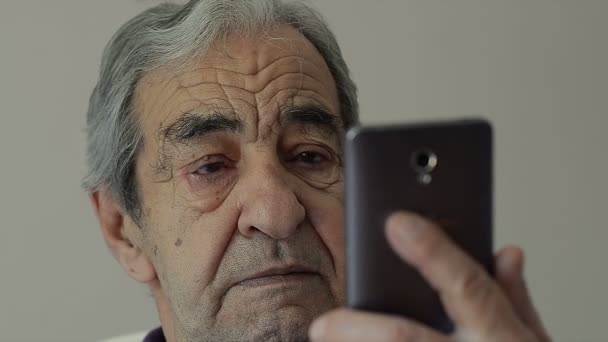 Крупный план старика читает SMS на мобильном телефоне — стоковое видео