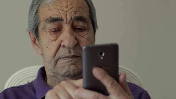 Закрыть пожилого пенсионера с помощью смартфона дома — стоковое видео