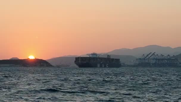 Geladen Container Cargo schip verlaat de haven bij zonsondergang — Stockvideo