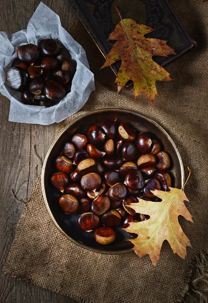 Geroosterde kastanjes in pan op rustieke achtergrond — Stockfoto