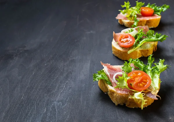 Crostini antipasti italiano con jamón, ensalada y tomate —  Fotos de Stock