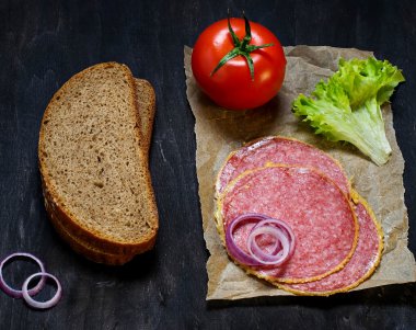 Sandviç için malzemeler: ekmek, domates, salam, salata, soğan