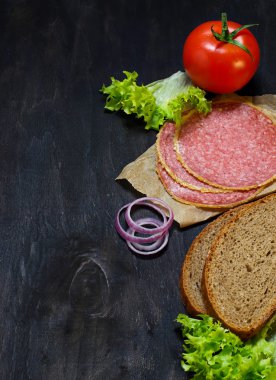 Sandviç için malzemeler: ekmek, domates, salam, salata, soğan