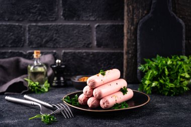 Arka planda baharatlı haşlanmış domuz sosisi.