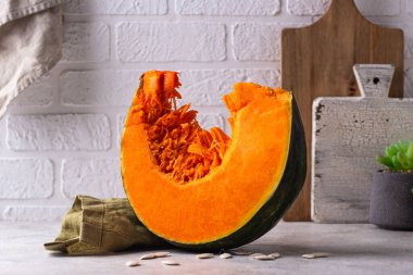 Dilimlenmemiş çiğ balkabağı ve beyaz mutfakta tohum.