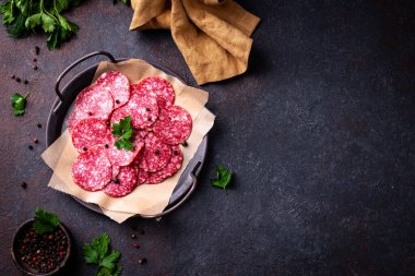 Dilimlenmiş baharatlı lezzetli salam sosisi, koyu arkaplanda.