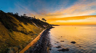 Vivid glowing orange sunset over scenic coastline in Australia - aerial view clipart