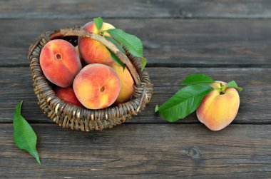 Olgun sulu şeftali meyveleriyle dolu sepet kırsal ahşap bir masada..