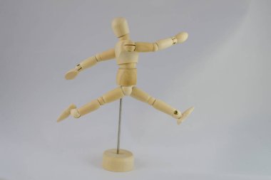 Beyaz bir arka planda koşucu pozu veren eklemli bir manken.