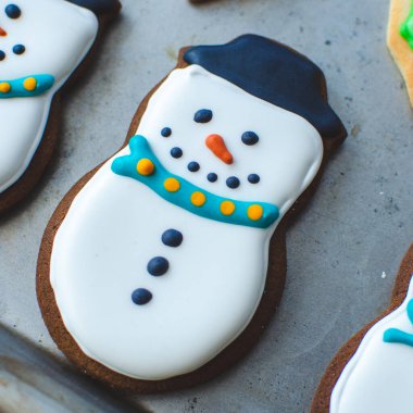 Mutlu bir kardan adam gibi görünmek için süslenmiş sevimli bir Noel kurabiyesi.