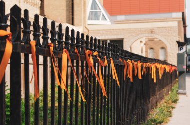 orange ribbons tied to a wrought iron fence outside Saint Mary's Cathedral, Winnipeg, Manitoba, Canada  clipart