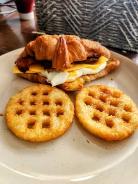 Pastırmalı, yumurtalı, peynirli ve soğanlı kruvasan sandviçi.