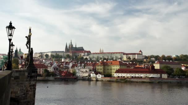 カレル橋の街路灯14世紀のプラハ城と聖ヴィート大聖堂を背景に 旧市街中心部の夕日にはヴルタヴァ川が流れています — ストック動画