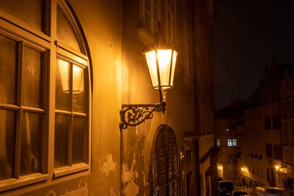 light from a lit street light in a city street at night. glowing lamp at night in the old town of prague in the czech republic