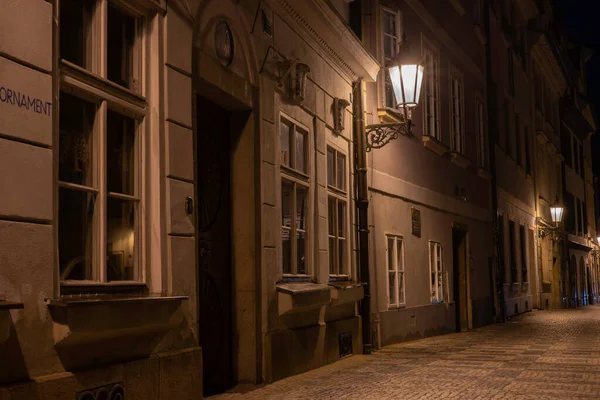 light from a lit street light in a city street at night. glowing lamp at night in the old town of prague in the czech republic