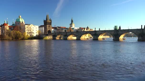 statický záběr na Karlův most a tekoucí řeku Vltavu ve středu Prahy při západu slunce obloha je v České republice modrá