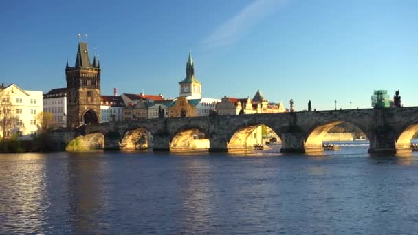 pohybující se záběr na Karlův most a tekoucí řeku Vltavu ve středu Prahy při západu slunce obloha je v České republice modrá