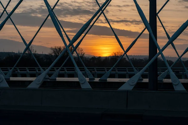 日落时在城镇中心的河上建造一座交通桥梁 背景中阳光和阳光照亮了天空 — 图库照片
