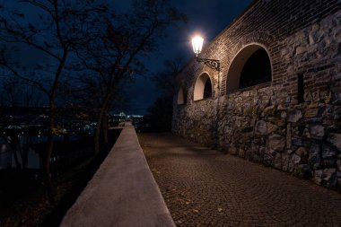 Sokak lambalarından ve kalenin 15. yüzyıldan kalma taş duvarlarından gelen ışık ve geceleyin Prag 'ın merkezinde, sonbaharda yayalar için kaldırım taşları.