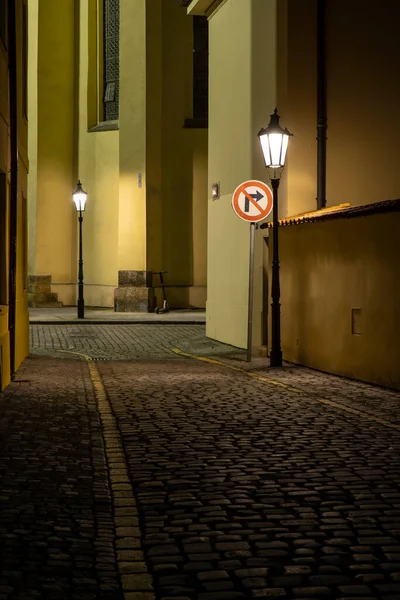 street lights on an illuminated street and pebbles on the ground in the center of the old town of prague at night in the czech republic