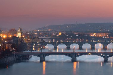 Vltava Nehri 'nin manzarası, nehir üzerindeki köprüler, Charles Köprüsü ve geceleri Prag şehrindeki sokak lambaları. 