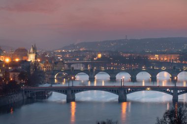Vltava Nehri 'nin aydınlık manzarası ve nehir üzerindeki köprüler ve Charles Köprüsü ve geceleri Prag şehrindeki sokak lambaları. 