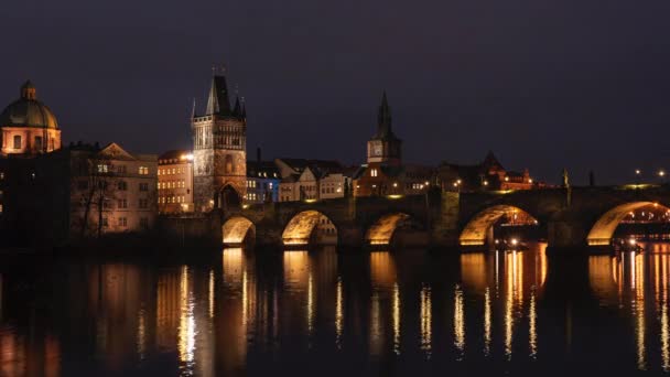 statický pohled na osvětlený kámen Karlův most a tekoucí řeku Vltavu a světla z pouličního osvětlení v centru Prahy v České republice v noci