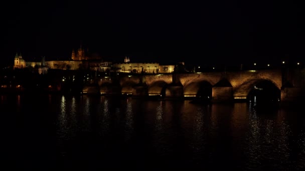 Statische Ansicht der beleuchteten Karlsbrücke aus Stein und des fließenden Flusses Moldau und Beleuchtung der Straßenbeleuchtung im Zentrum von Prag in der Tschechischen Republik bei Nacht