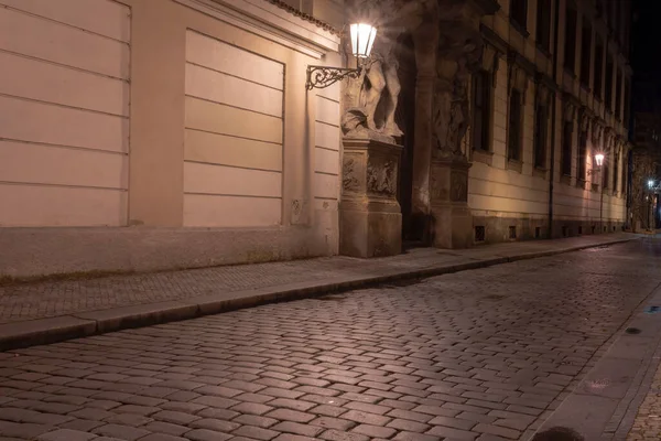 lit street lights and a cobbled street with cobblestones in the center of Prague at night