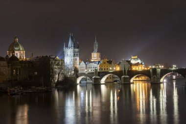 Vltava Nehri 'ndeki Charles Köprüsü ve Prag' ın merkezindeki sokak lambalarından gelen ışık.
