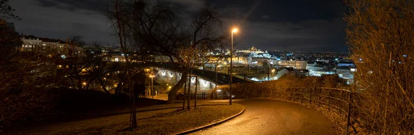 street lights and pedestrian walkway in the park and in the background a view of the city of prague and prague castle at night in the center of prague in the czech republic