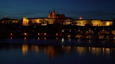 Vltava Nehri 'nin akışını ve Prag' ın merkezinde, gün batımında Charles Köprüsü 'ndeki kuleyi gösteren görüntü.