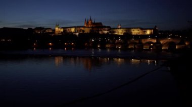Vltava Nehri 'nin akışını ve Prag' ın merkezinde, gün batımında Charles Köprüsü 'ndeki kuleyi gösteren görüntü.