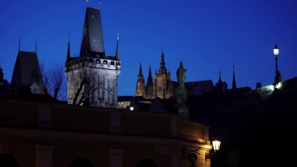 カレル橋とプラハ城 聖ヴィート大聖堂を背景にした囚人たちの街路灯のシルエットを夜明けにご覧ください — ストック動画
