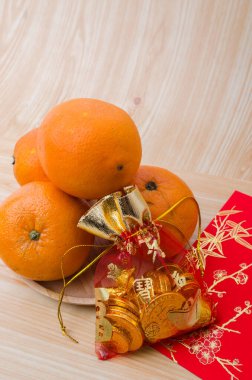 Çin Yeni Yılı - Beyaz boyanmış ahşap masa üzerinde Çince turuncu, altın sicee (yabancı metin zenginlik anlamına gelir) ve kırmızı paket (yabancı metin bahar sezonu anlamına gelir)