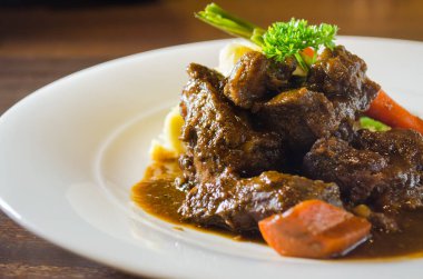 Biftek yahnisi, yanında sebze ve patates püresi ile servis edilir. Seçici odak