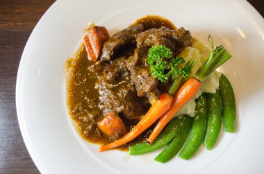 Biftek yahnisi, yanında sebze ve patates püresi ile servis edilir. Seçici odak