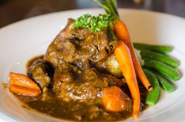 Biftek yahnisi, yanında sebze ve patates püresi ile servis edilir. Seçici odak