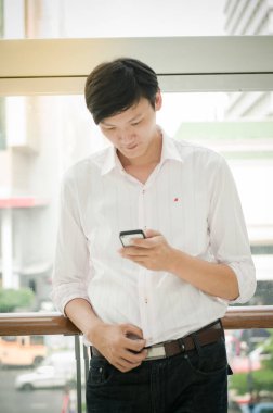 Asyalı adam. Modern ofiste cep telefonuna bakan bir işadamı