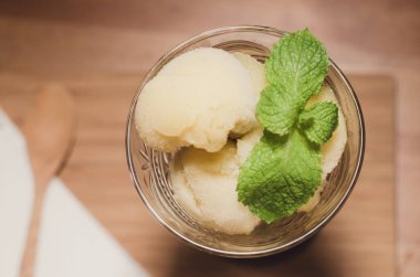 Bardakta mango dondurması. Tahta bir masaya yerleştirilmiş.