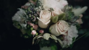 Hassas bir buket büyük ve küçük açık pembe gül, yeşil sulu sulu, beyaz çigila ve kurumuş çiçekler ve koyu yeşil bir bitki arka planında küçük meyveler.