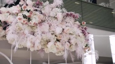 Farklı taze çiçeklerden oluşan büyük bir buket: şakayıklar, metal beyaz tırabzanlara tutturulmuş ortancalar. Aşağıdan yakın çekim.