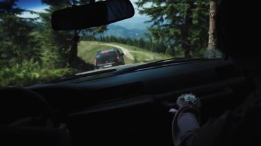 Bir çift beyaz adam, bir kadın ve bir erkek, çamlık ormanın ortasındaki toprak yolda sola doğru ağır ağır giden bir arabaya biniyorlar ve önlerindeki çimlere, dağlara bakan siyah arabaya gidiyorlar.