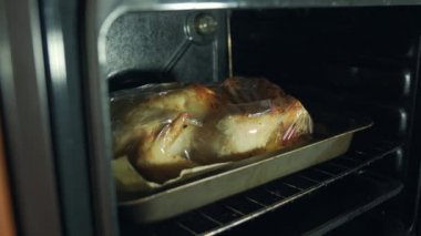 Noel 'de insanlar bayram onuruna taze ve sulu etin tadını çıkarmak için bir yemek torbasında tavuk pişirirler. Yan görüş, hareket kamerası mutfak duvarı dekoya.