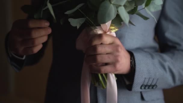 양복을 셔츠를 시계를 남자가 어두운 손으로 분홍색 모양의 꽃다발을 유칼립투스 — 비디오
